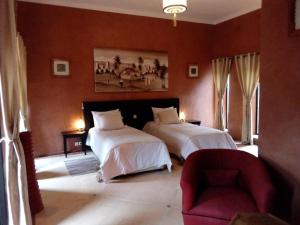 - une chambre avec deux lits, une chaise et un canapé dans l'établissement Villa Malaa'ika, à Marrakech