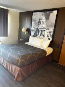 un letto in una camera con una foto di un edificio di Super 8 by Wyndham Smithville a Smithville