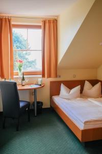 a hotel room with a bed and a desk and a window at Landhotel Dresden in Dresden