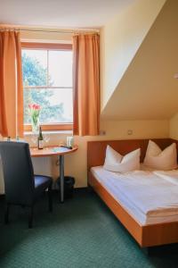 a hotel room with a bed and a desk and a window at Landhotel Dresden in Dresden