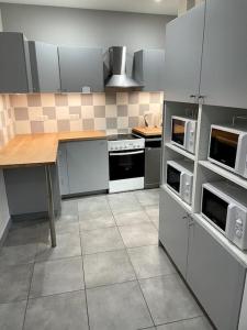 a kitchen with white appliances and a table in it at Belle et agréable maison de ville 9 chambres in Saint-Étienne