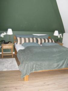 2 camas en un dormitorio con una pared verde en Ferienwohnung Storchennüst en Aurich