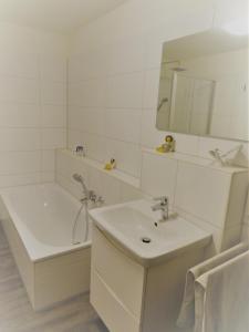 La salle de bains blanche est pourvue d'une baignoire et d'un lavabo. dans l'établissement Haus Nr 11, Ferienhaus Fischerhus, à Wangerland