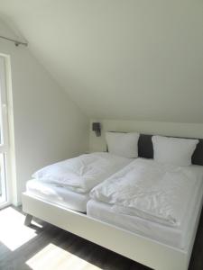 - un lit blanc avec des draps et des oreillers blancs dans l'établissement Haus Nr 11, Ferienhaus Fischerhus, à Wangerland