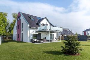 una casa bianca e rosa con un cortile verde di VILLA MON BIJOU _ OG_Fewo a Göhren-Lebbin