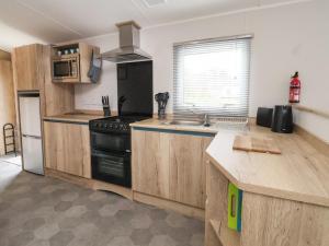 a kitchen with wooden cabinets and a black stove at Walkers Retreat in Ganton