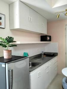 eine Küche mit weißen Schränken, einer Spüle und einer Pflanze in der Unterkunft Cozy Flexi 1BR or 2BR condo at Southmall Las Pinas in Manila