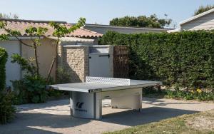 a ping pong table in front of a house at Camping Les Perouses in Saint-Clément-des-Baleines