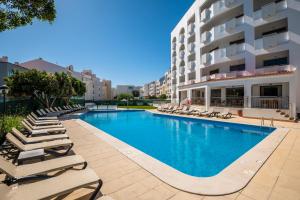 a swimming pool with lounge chairs and a building at Emeralds Albufeira in Albufeira