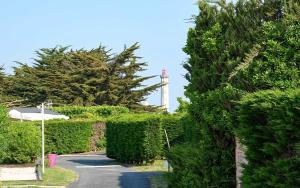 a hedge yard with a lighthouse in the background at Camping Les Perouses in Saint-Clément-des-Baleines