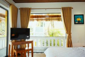 a bedroom with a bed and a tv and a window at An Nam Hue Boutique in Cư Chinh