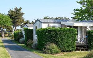 a small white house with a porch and bushes at Camping Les Perouses in Saint-Clément-des-Baleines