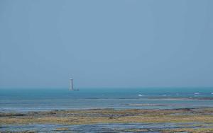 a view of the ocean with a lighthouse in the distance at Camping Les Perouses in Saint-Clément-des-Baleines