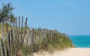 a wooden fence on a beach next to the ocean at Camping Les Perouses in Saint-Clément-des-Baleines
