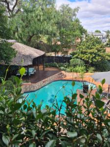 a swimming pool in a yard with a thatch roof at Halfway Gardens Home in Midrand