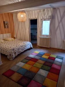 a bedroom with a bed and a colorful rug at La Maison de Chouquette in Limoux