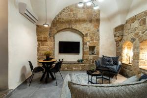 un soggiorno con parete in pietra, tavolo e sedie. di Mirsa a ‘Akko