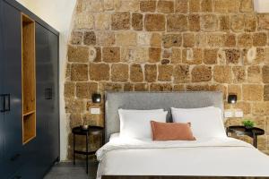 una camera da letto con un muro in pietra e un letto di Mirsa a ‘Akko
