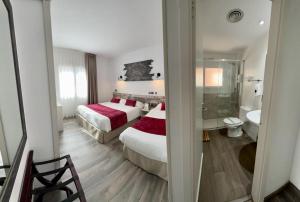 a hotel room with two beds and a bathroom at Hotel Bella Dolores in Lloret de Mar