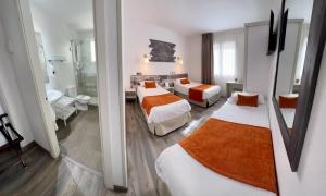 a hotel room with two beds and a bathroom at Hotel Bella Dolores in Lloret de Mar