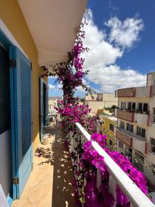 un balcone con fiori viola su un edificio di B&B Mi Ma Bo, Sal Rei, Boa Vista, Cape Verde, FREE WI-FI a Sal Rei