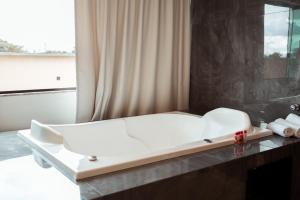 uma cama branca num quarto com uma janela em Miami Hotel by H Hotéis - Business em Taguatinga