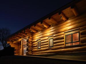 a log cabin with lights on the side of it at Aurora in Bushmills
