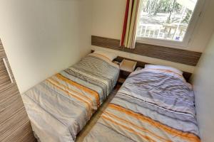 two beds in a small room with a window at Camping Domaine de la Paille Basse - Maeva in Souillac