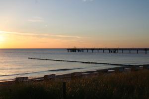 a beach with benches and a pier in the ocean at Appartement Louise in Wustrow