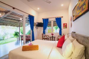 Schlafzimmer mit einem großen Bett und blauen Vorhängen in der Unterkunft Be's Beach House An Bang in Hoi An