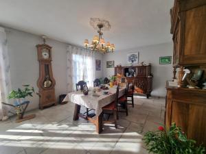 a dining room with a table and a grandfather clock at Au plein soleil in Chazelles-sur-Lyon