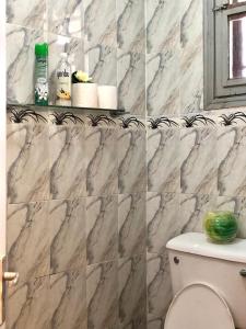 a bathroom with marble tile walls and a toilet at Elegant 1br Milimani - Fast Wifi in Kisumu