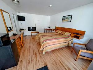 Habitación de hotel con cama y TV en Motel Bonsoir, en Joliette