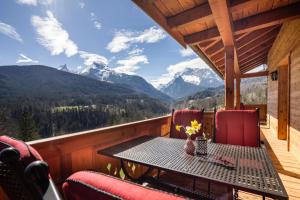 a table and chairs on a balcony with mountains at Bergbauernhof Schoberlehen in Bischofswiesen