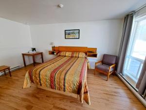 a bedroom with a bed and a chair at Motel Bonsoir in Joliette