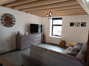 ein Wohnzimmer mit einem Sofa und einem Flachbild-TV in der Unterkunft Clénoliette in Cerfontaine