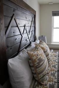 Bett mit einem Kopfteil aus Holz und Kissen darauf in der Unterkunft Pine Lodge in Encampment