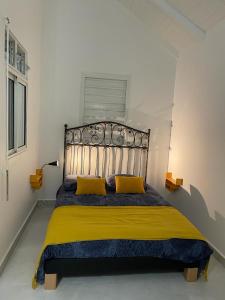 ein Bett mit zwei gelben Kissen in einem Schlafzimmer in der Unterkunft Nid D amour in Petit-Bourg
