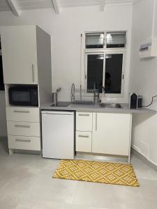 eine Küche mit weißen Schränken, einem Waschbecken und einem Fenster in der Unterkunft Nid D amour in Petit-Bourg