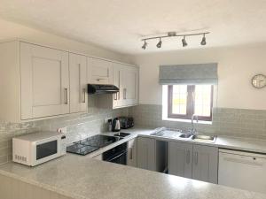 a kitchen with white cabinets and a microwave at Little Norton Mill in Chiselborough