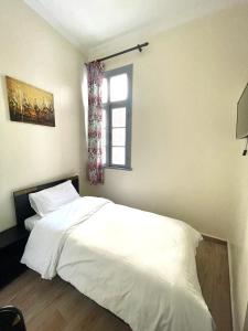 Hotel Mauritania في طنجة: غرفة نوم بسرير ابيض ونافذة