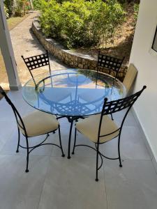 une table en verre avec quatre chaises autour de la terrasse dans l'établissement Nid D amour, à Petit-Bourg