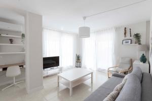 Sala de estar blanca con sofá y mesa en ATICO EN PRIMERA LÍNEA MEDITERRANEO, en Peñíscola
