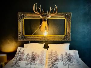 a picture with a deer head above a bed at Domaine de la Croix de Saint Lambert in Poix-Terron