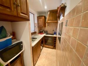 una pequeña cocina con armarios de madera y encimera en Charmant appartement T2 65m² en Quenza