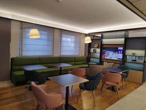 una sala d'attesa con divano verde, tavoli e sedie di Holiday Inn Salerno-Cava De' Tirreni, an IHG Hotel a Cava deʼ Tirreni