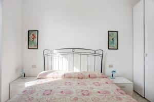 Dormitorio blanco con cama con colcha rosa en House Mario, en Levanto