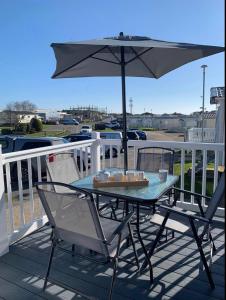 a table and chairs with an umbrella on a deck at Sea La Vie in Cayton