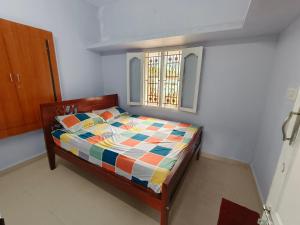 a bedroom with a bed with a colorful comforter and a window at SM GARDENS Nature Stay Kodaikanal in Oothu