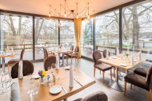 un restaurante con mesas, sillas y ventanas grandes en Haus am Spreebogen, en Fürstenwalde